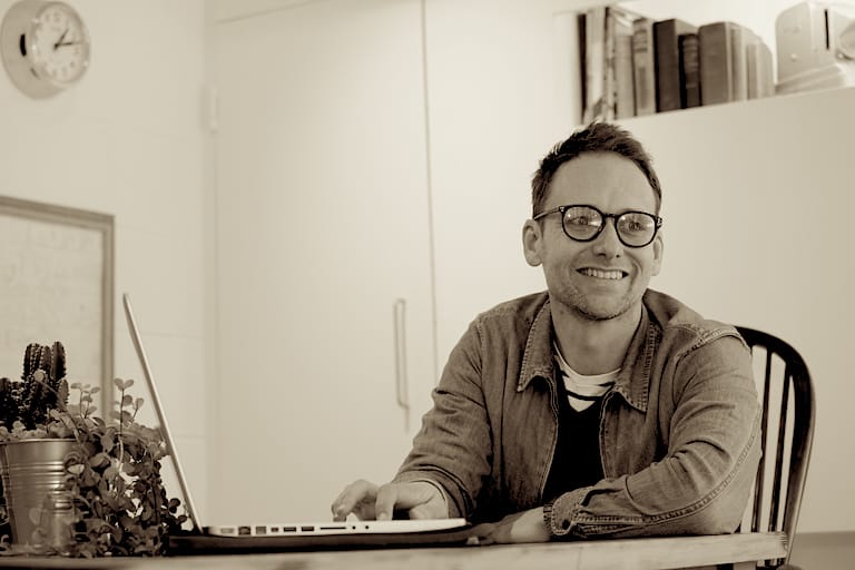 Sacha Harmsworth smiling while working at a laptop